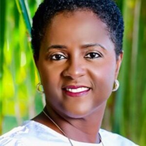 A portrait of Claudette Davis. She is a black woman with short natural hair and a white blouse