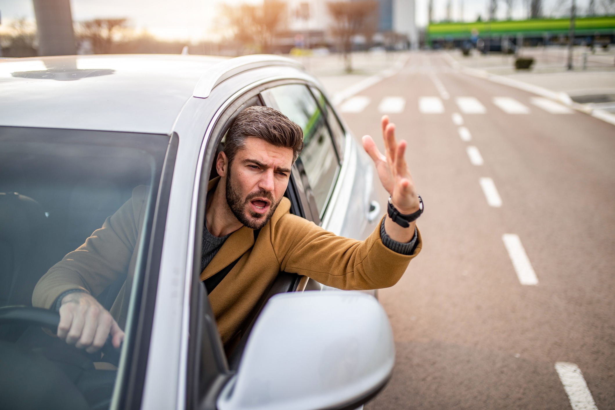 A man leaning out of his white car and shouting