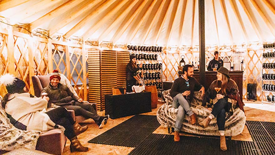 Several people in warm clothes talking in a private yurt at Grand Hyatt Vail