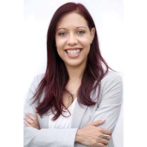 A portrait of Jennifer Bello. She is a brown woman with long red hair and a grey suit jacket