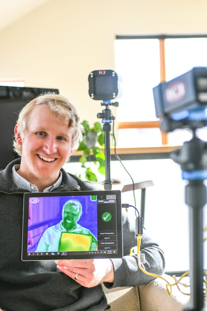 A portrait of John Harris holding an iPad connected to a heat mapping camera
