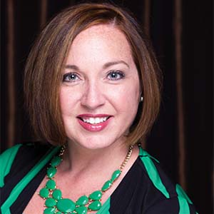 A portrait of Karen Hartline. She is a white woman with chin-length brown hair and a black and teal blouse