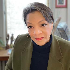 A portrait of Kelli A. Bland. She is a black woman with short straight hair and a dark suit jacket