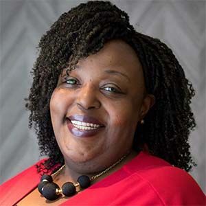 A portrait of Lakesha Moore. She is a black woman with shoulder-length natural hair and a red blouse