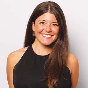 A portrait of Lindsay Kushner. She is a white woman with long blonde hair and a sleeveless black blouse