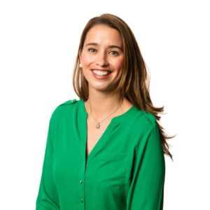 A portrait of Nicole McCoy. She is a white woman with long brown hair and a green blouse