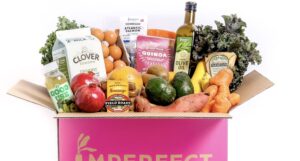 A pink box from Imperfect Foods holding produce, milk and other groceries