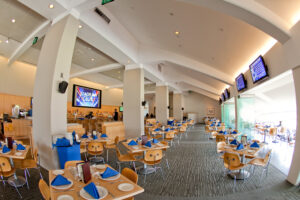 The Stadium Club in Dodger Stadium. There are wooden tables and chairs set with blue napkins