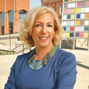 A portrait of Susie Townsend. She is a blonde white woman with short wavy hair and a blue blouse