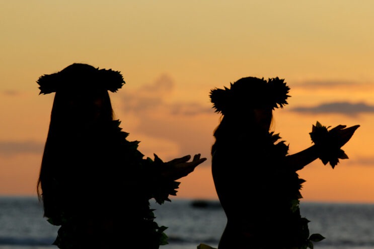 Two silhouetted hula dancers at sunset