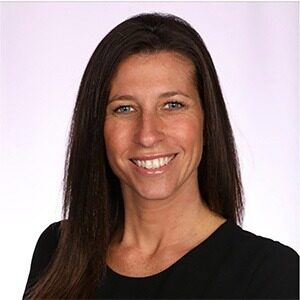 A portrait of Jamie Gold. She is a tan white woman with long brown hair and a black blouse