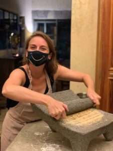 Ashley Lawson using a stone rolling pin to process a yellow powder in a cooking class