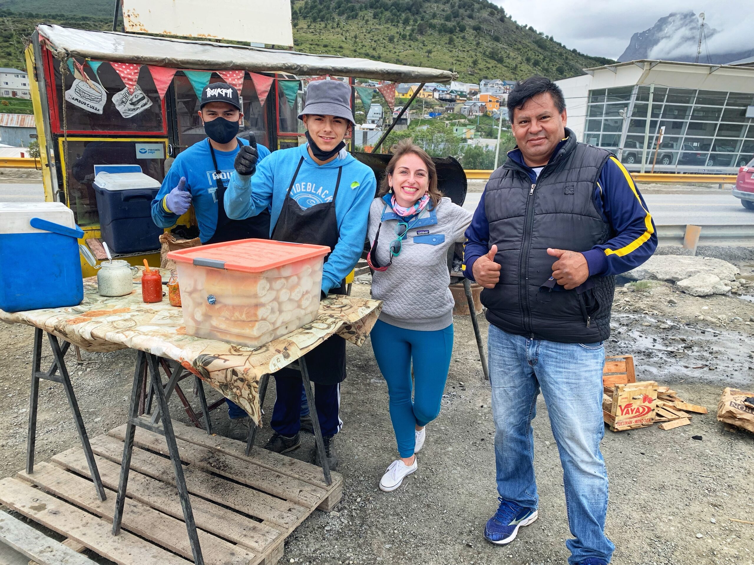 Ashley Lawson and Freddie posing with two Argentinian locals next to a small food stall