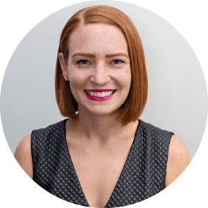 A portrait of Molly Witges. She is a white woman with shoulder-length red hair and a patterned black blouse