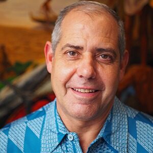 A portrait of Ed Braunlich. He is an older balding man with a blue collared shirt.