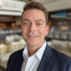 A portrait of Skip Harless. He is a white man with combed brown hair and a suit jacket.