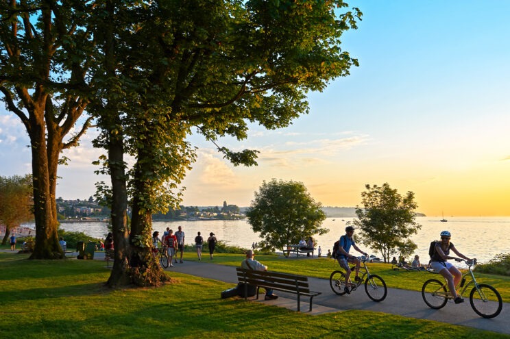 People biking on a path next to a lake.