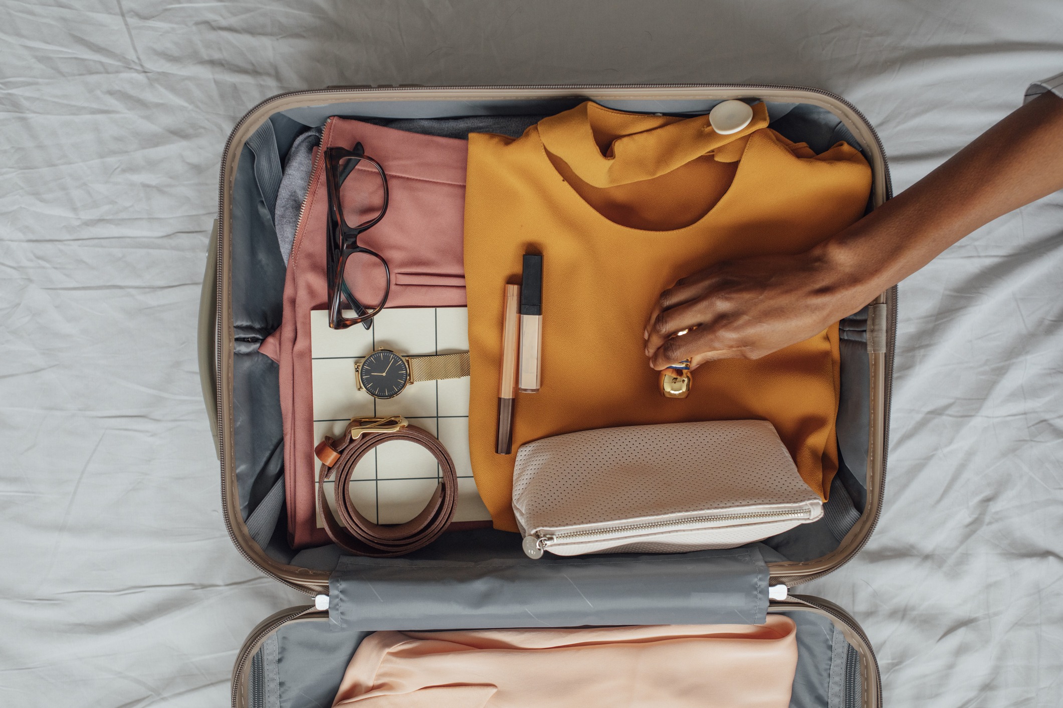 A person packing a suitcase on a bed.