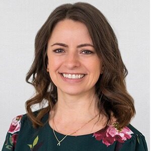 A portrait of Michelle Haider. She is a white woman with loosely curled brown hair and a floral blouse.