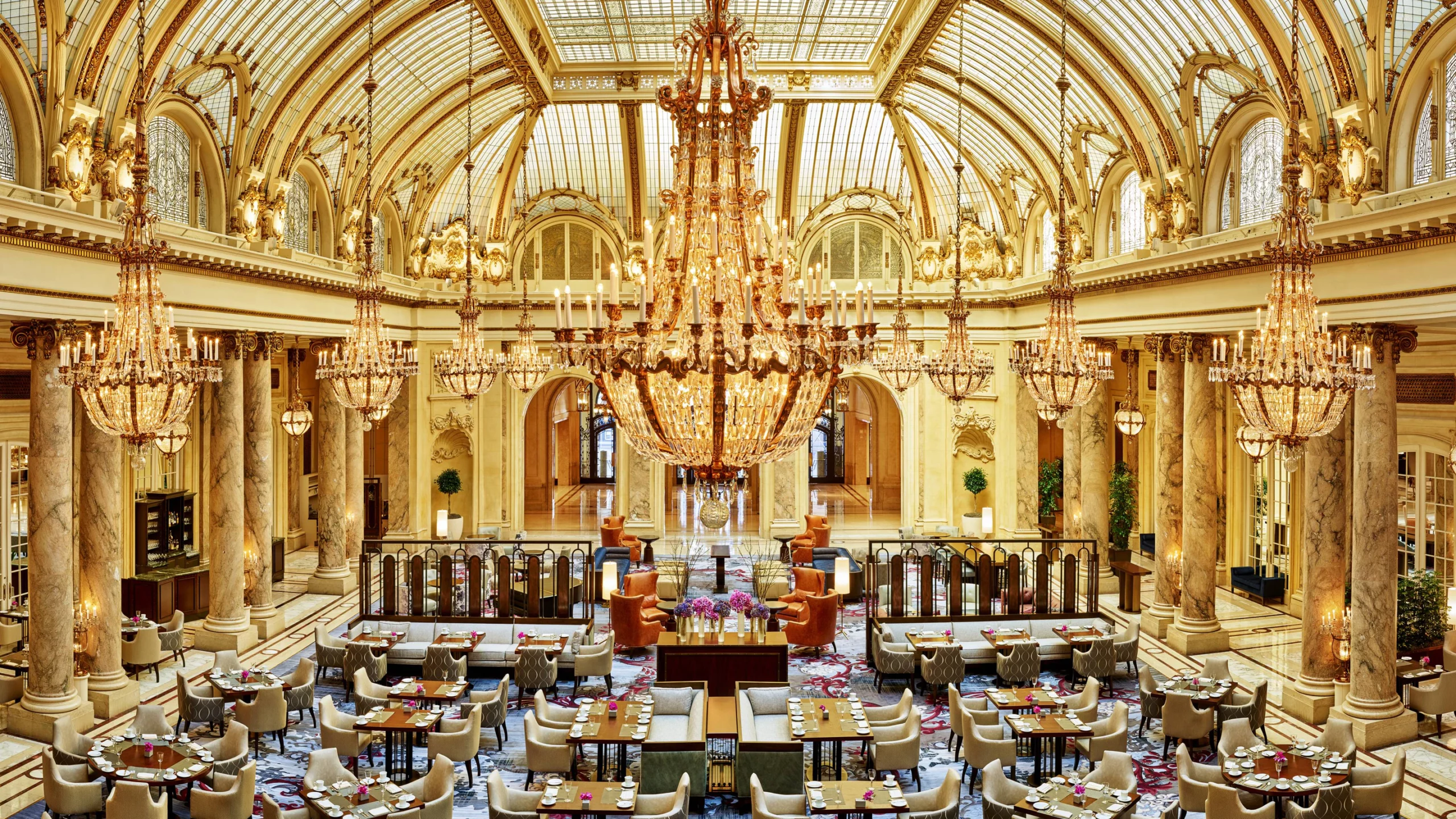 A meeting space in Palace hotel in San Francisco. It has a highly detailed yellow interior with a series of tables and chairs.