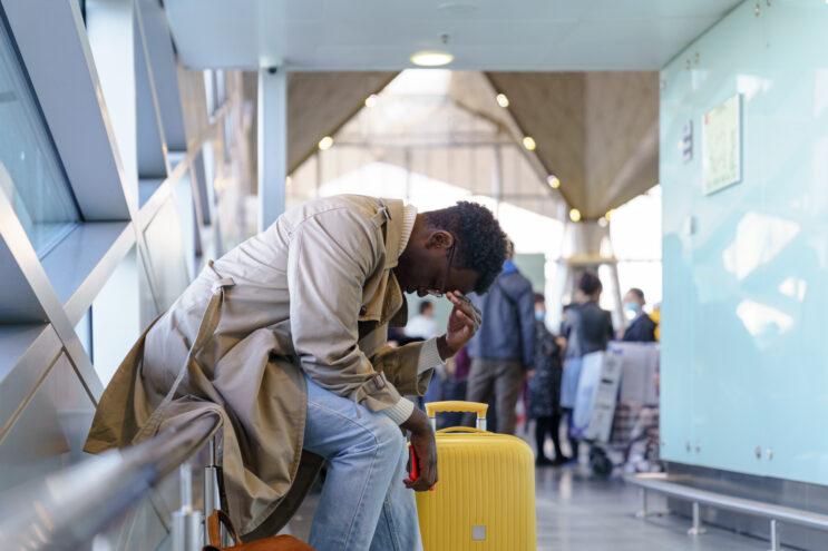 A man is hunched over in an airport. Even with masks no longer required on European flights, travelers are still unhappy.