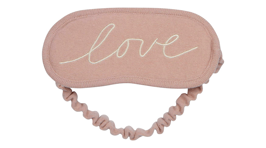 A pink plush sleeping mask with "love" written in white cursive