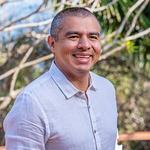 A portrait of Ronny Fernández. He is an older Mexican man with a grey collared shirt.