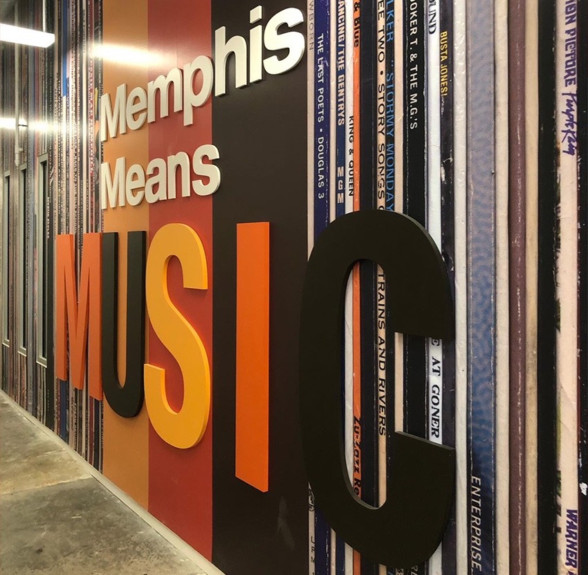 A wall in the Memphis Crosstown Concourse, with text reading, "Memphis means Music." The wall depicts oversized vinyl spines lined up next to each other.