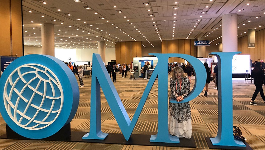 An oversized MPI logo in a convention hall, with Smart Meetings founder Marin Bright.