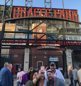 Several people taking a selfie in front of Oracle Park in San Francisco.