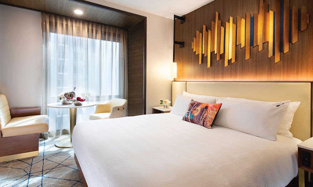 A hotel room in the Hard Rock Hotel New York. A king-sized bed is below a wood panel decoration. The newly renovated property is open now.