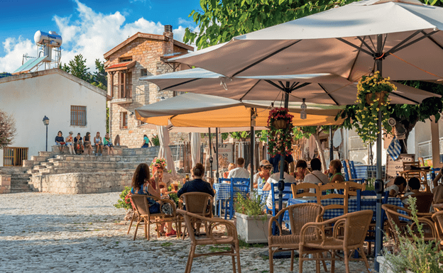 The Oenou Yi Winery on the island of Cyprus. People sit on chairs under tan umbrellas
