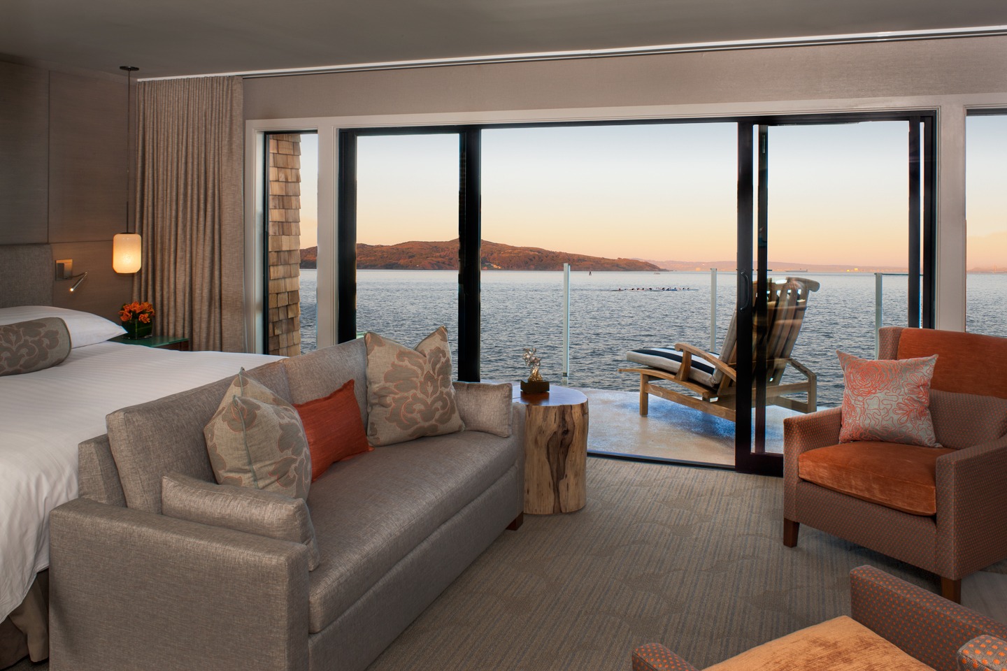 A view from a room in The Inna Above Tide. The bay is outside a private deck with a chair. A small sitting area is at the end of the bed.