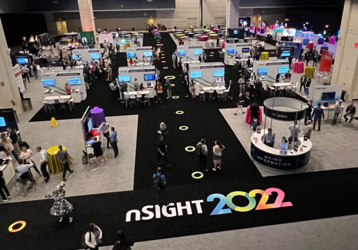 The convention floor of nSight 2022. Booths with TVs are set between a black walkway.