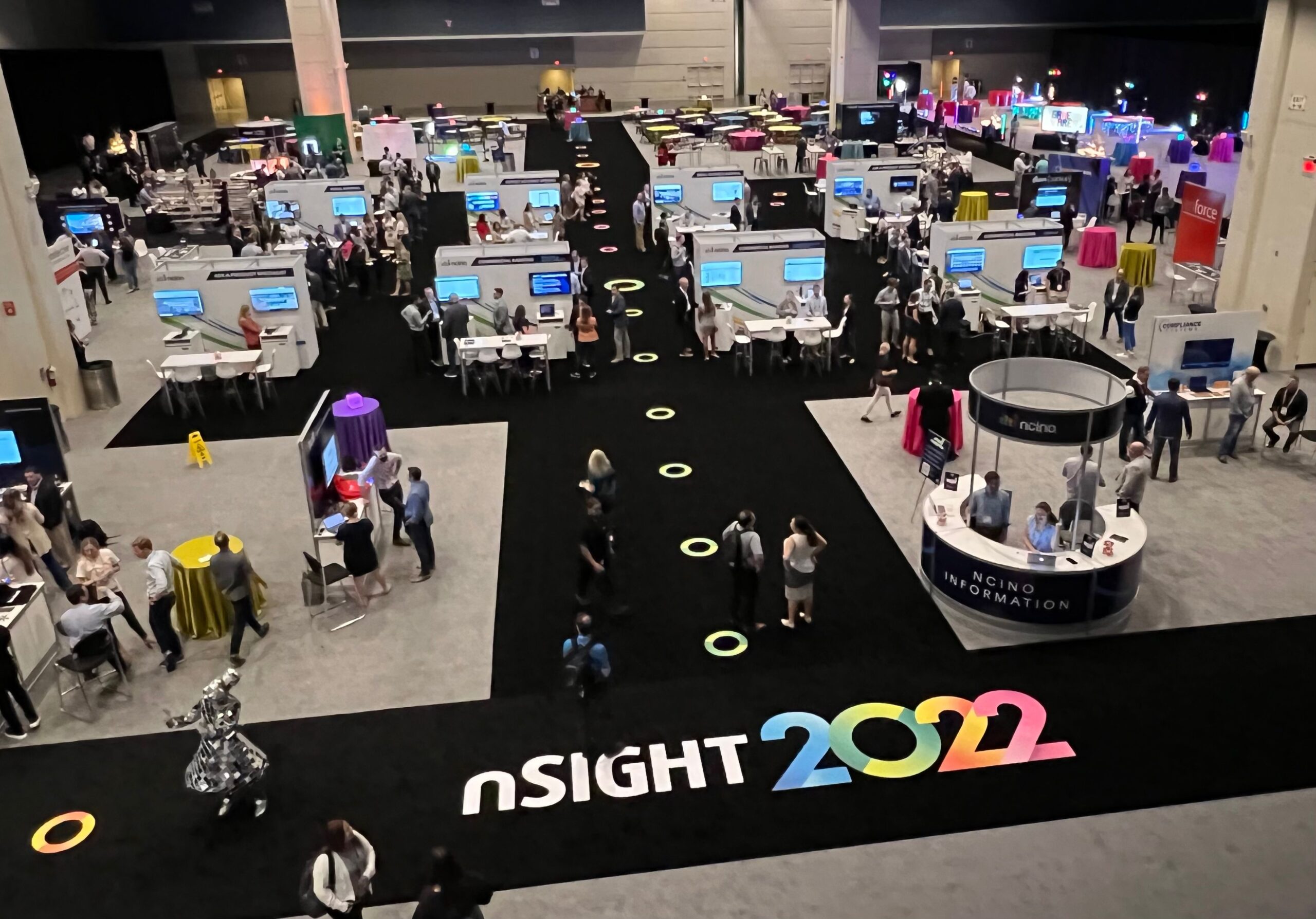 The convention floor of nSight 2022. Booths with TVs are set between a black walkway.