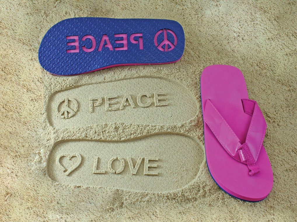 A pair of flip-flops, pink on top and blue on the bottom, with cutouts that read "peace" and "love" on each foot