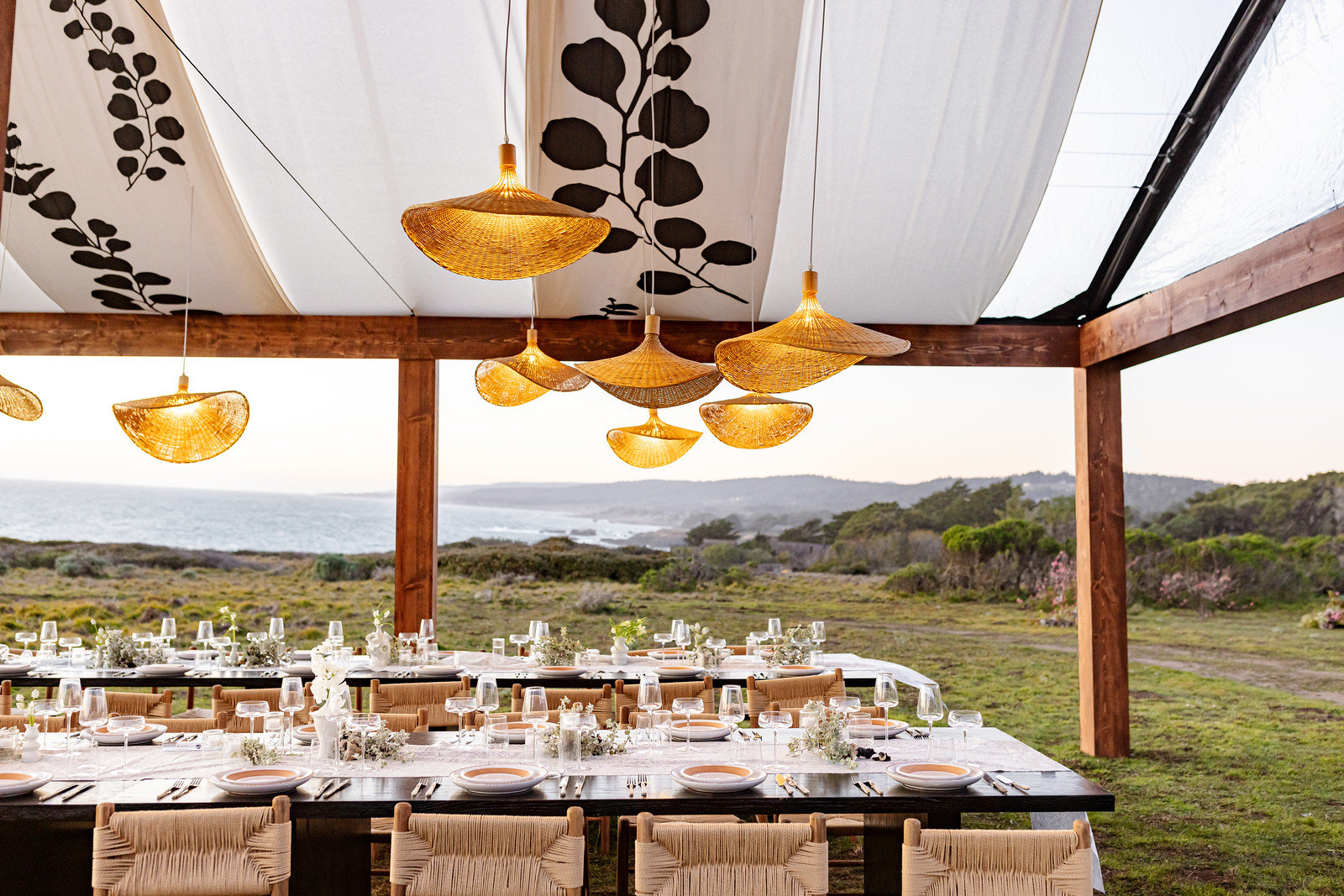 An outdoor banquet table with a cloth tent and orange lights above