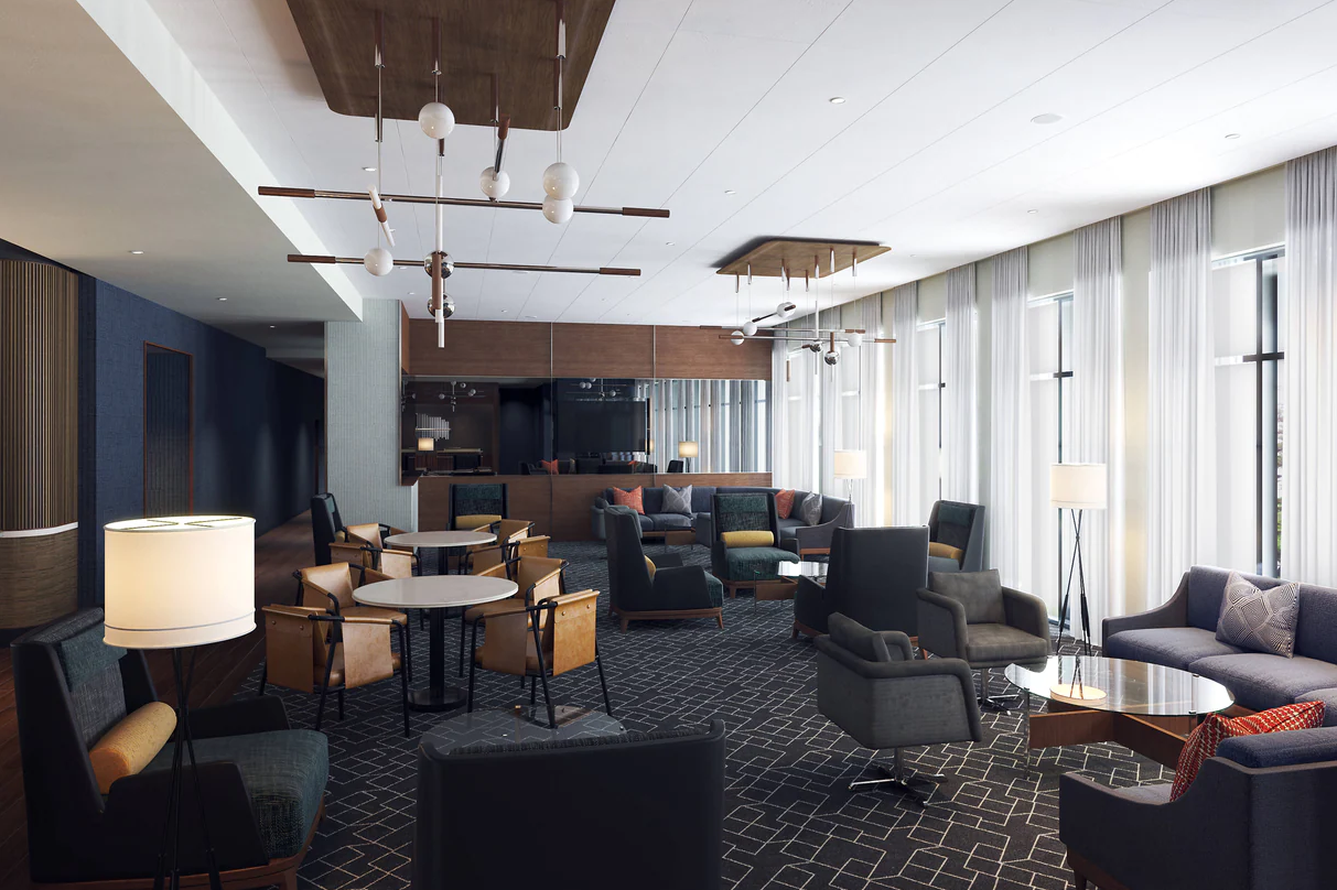 The newly renovated lounge of Courtyard by Marriott San Diego Miramar. Dark grey couches and carpets are next to white-curtained windows.