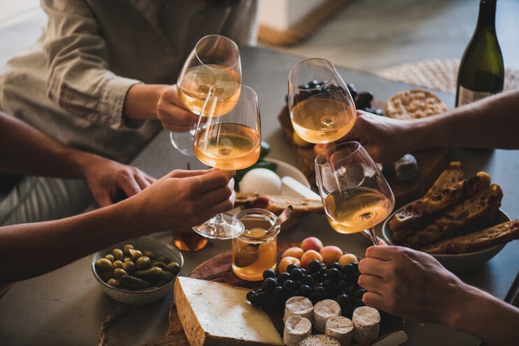 Friends having wine tasting or celebrating event with drinking