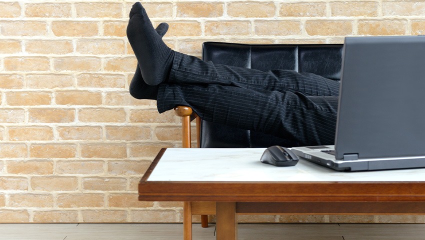 businessman laying down on couch in front of computer