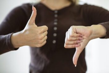 woman giving thumbs up with right hand and thumbs down with left hand