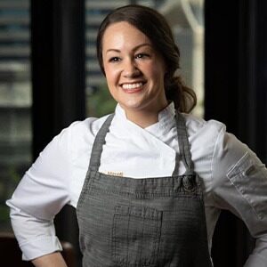 danielle marelli wearing white chef coat under grey apron