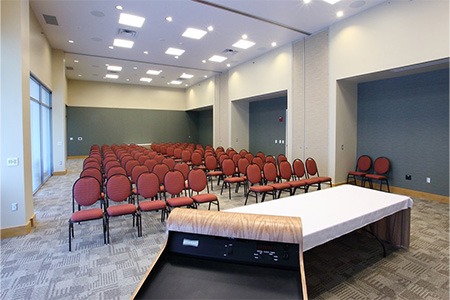 meeting space with rows of red chairs and white table at the front of the room