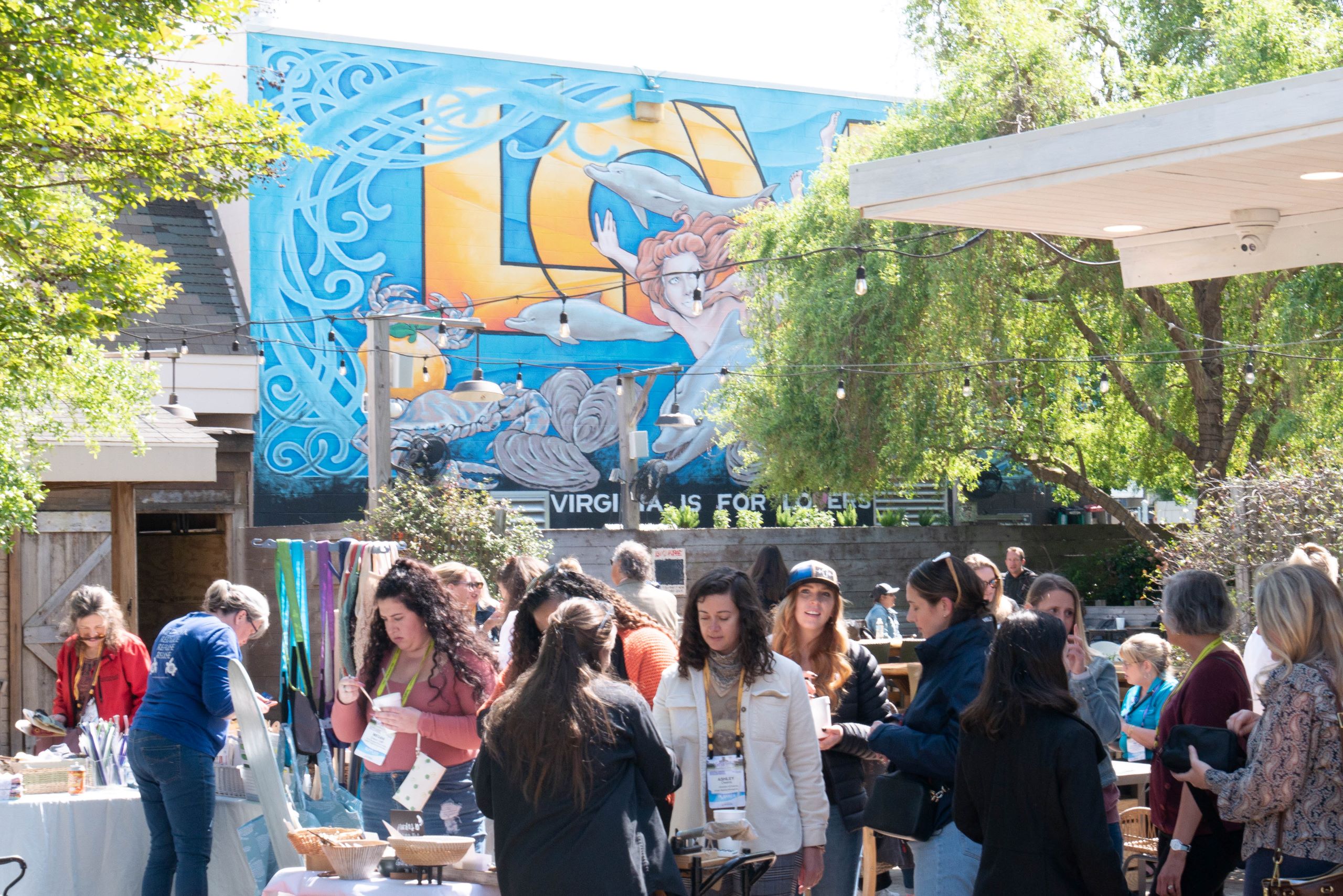 large number of people talking in front of mural