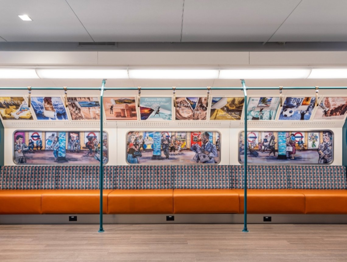 A long orange bench sits in front of walls painted to look like the London Underground