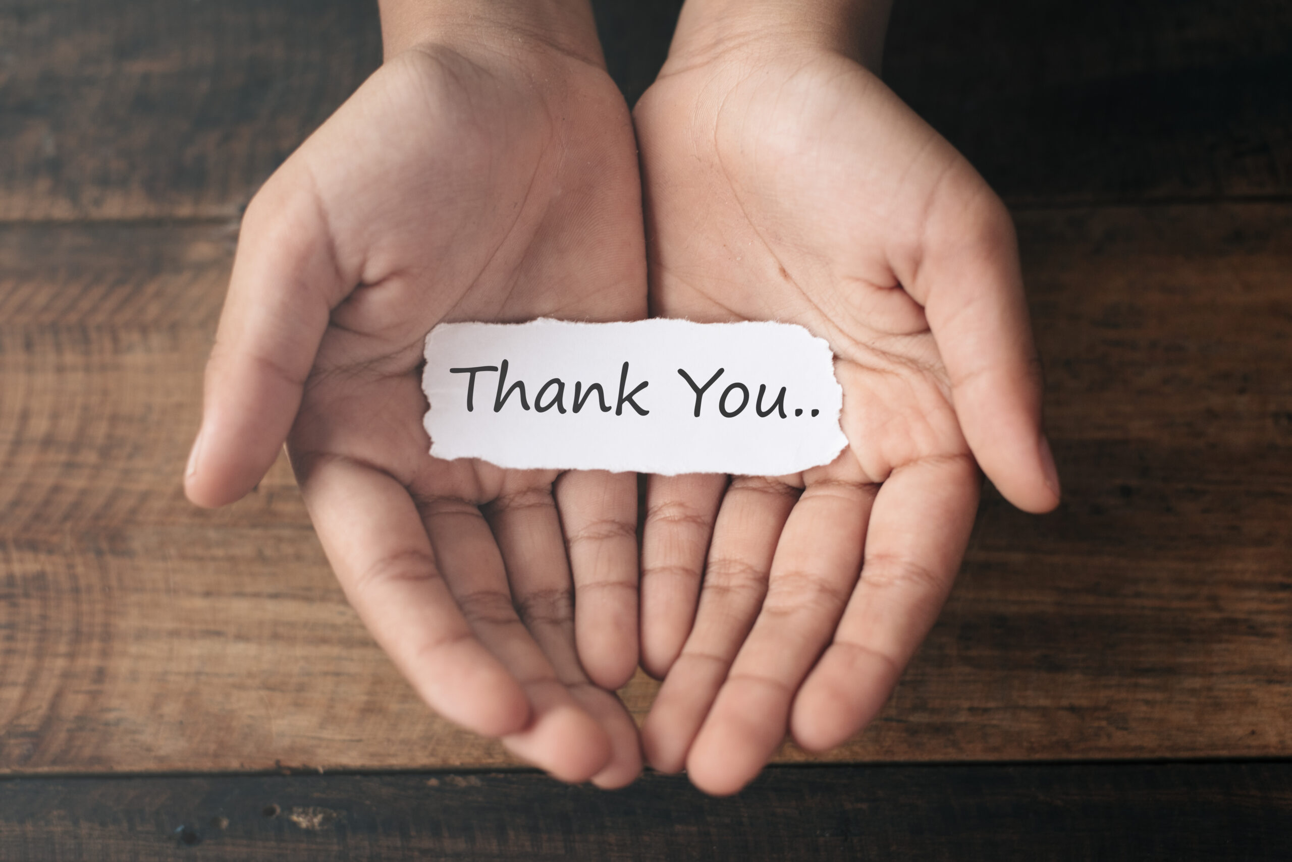 hands holding 'thank you' note