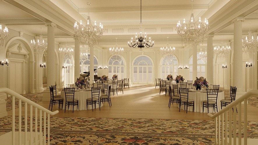 The Crystal Room at The Omni Homestead Resort has warm lighting with crystal chandeliers, columns, carpet and round tables with tablecloths and chairs