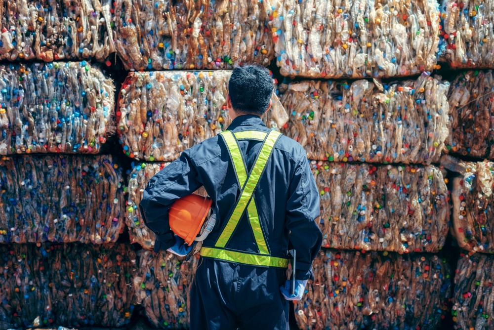 man standing in front of pallets of plastic bottles